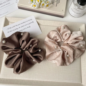 Close-up of elegant satin scrunchies with white pearls in coffee and champagne pink tones