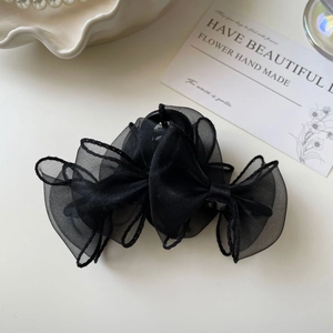 Détail d'une pince à cheveux élégante en organza noir avec double nœud en tulle doux