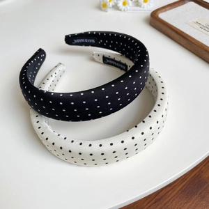 Detailed view of padded polka dot headbands with handmade label on white surface