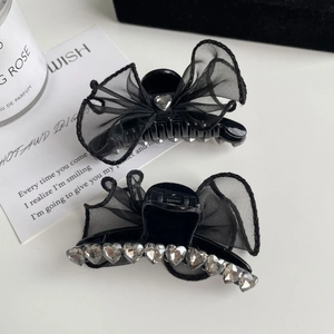 Détail de deux barrettes à nœuds en résille noire avec des ornements en cristal en cœur