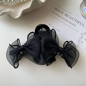 Détail d'une pince à cheveux élégante avec nœud en organza noir sur un plateau décoratif