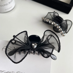 Gros plan de barrettes à nœud en résille noire avec strass en cœur et finition polie