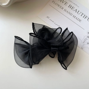 Détail d'une pince à cheveux avec nœud en organza noir et texture de tissu multicouche