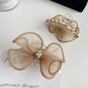 Détail de la pince à cheveux avec nœud en strass champagne et cristal en forme de cœur