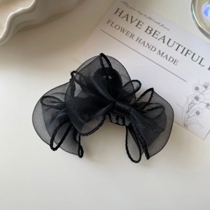 Vue détaillée d'une pince à cheveux avec nœud en organza noir sur fond blanc minimaliste