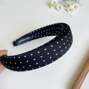 Detailed view of black polka dot headband with handmade label and foam filling padding