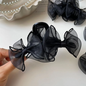 Détail d'une pince à cheveux élégante avec nœud en organza noir et texture translucide