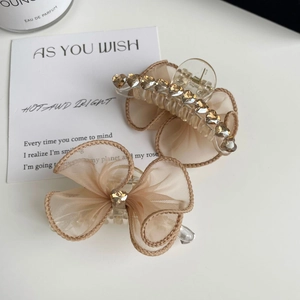 Détail de la pince à cheveux nœud champagne avec strass brillants et tissu en maille