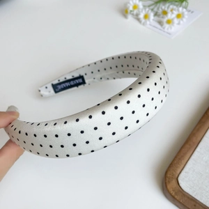Detail of white polka dot sponge headband with hand-made label and premium satin texture