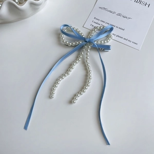 Detalle de horquilla con lazo azul claro y borlas de perlas blancas elegantes