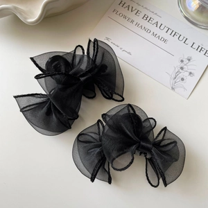 Vue détaillée de deux pinces à cheveux à nœuds en organza noir sur un plateau décoratif