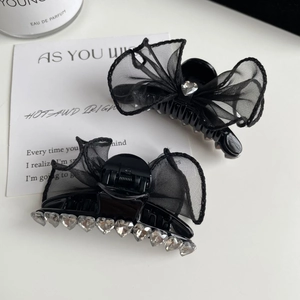 Détail de la pince à cheveux à nœud en résine noire avec strass en forme de cœur