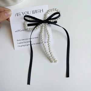 Detalle de una elegante pinza para el cabello con lazo negro y perlas blancas finas