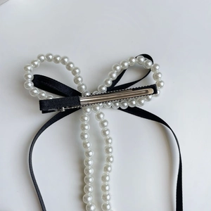 Detalle de la elegante pinza de pelo con lazo de seda negra y perlas blancas suaves