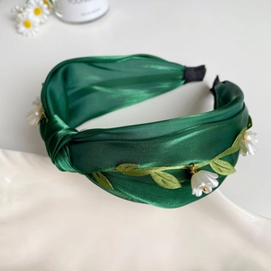 Detailansicht eines dunkelgrünen Satin-Haarreifs mit Blattstickerei und Blumenanhängern