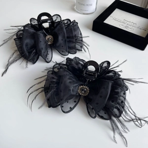 Detail of black polka dot mesh hair claw clip with feather accents and vintage gem