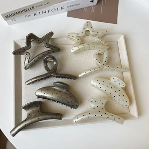 Polka dot hair claw clips in various shapes displayed on a minimalist beige tray