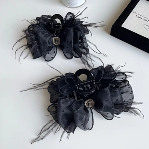 Detail shot of two elegant black feather hair claws with polka dot mesh bows and rhinestones
