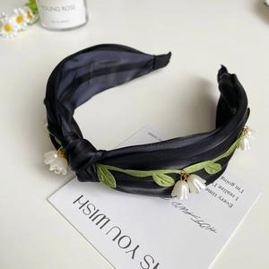 Detailaufnahme des schwarzen Satin-Haarreifs mit Maiglöckchen-Anhängern und Stickerei