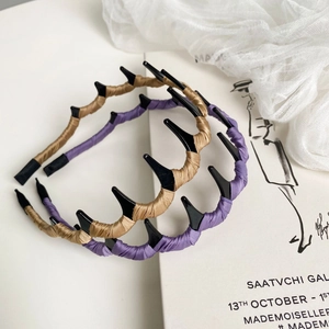 Détail de serre-têtes ondulés en tissu champagne et violet sur fond décoratif