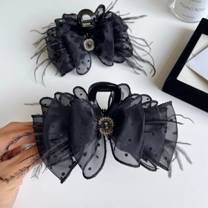 Detail of elegant black mesh bow hair claw with feathers and vintage rhinestone brooch