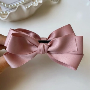 Dettaglio del fermaglio per capelli a fiocco in raso rosa con nastro di seta a strati