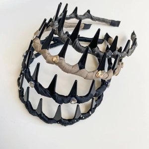 Detail of three intertwined rhinestone headbands in black, beige, and grey fabric