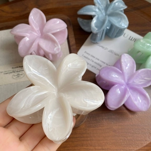Macro detail of glossy marble texture on plumeria flower hair claws in pastel colors