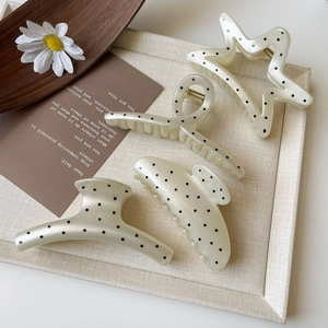 Detail view of four French style cream polka dot hair claws with pearl embellishments