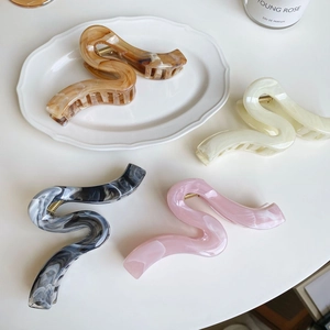 Détail du lot de quatre pinces à cheveux incurvées en ambre, crème, marbre et rose