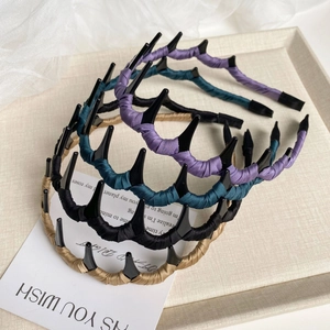 Détail de serre-têtes ondulés à dents en violet, vert foncé, noir et tissu doré
