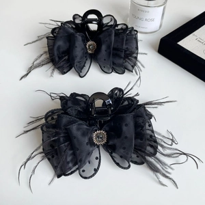 Detail view of large black mesh bow hair claw with feathers and a sparkling diamond center