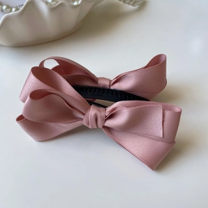Dettaglio del fermaglio a fiocco in raso rosa con trama elegante a strati di tessuto