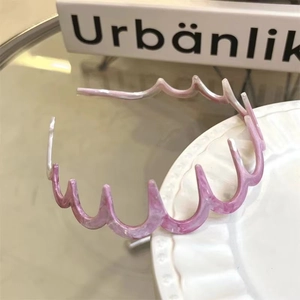 Dettaglio del cerchietto ondulato in acetato rosa marmorizzato con denti interni