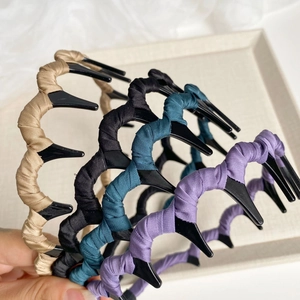Détail de quatre serre-têtes ondulés texturés en beige, noir, bleu cyan et violet