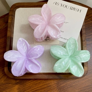 Three translucent flower hair claws in pink, purple, and green with marble texture