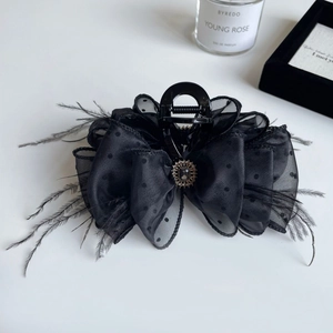 Macro shot of elegant black hair claw clip with polka dot mesh, feathers and jewelry stone