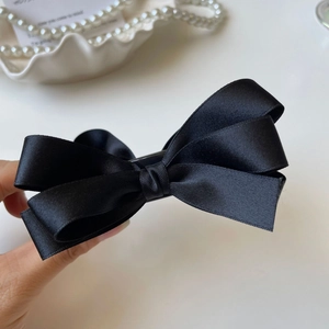 Dettaglio dell'elegante fermaglio per capelli a fiocco in raso nero dal design retrò