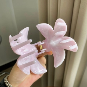 Close-up of pink frangipani hair claw clip with elegant marble texture and metal spring