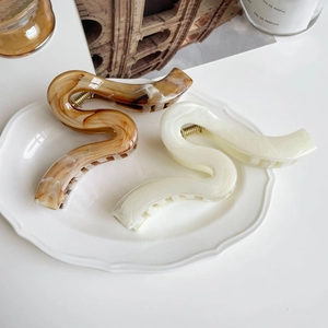 Détail de pinces à cheveux à vagues ambre et crème sur une assiette dans un style français