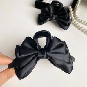 Dettaglio di un elegante fermaglio per capelli con fiocco in raso nero e trama di seta