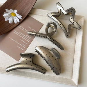 Detail view of four geometric hair claws with french polka dots on a stylish display tray