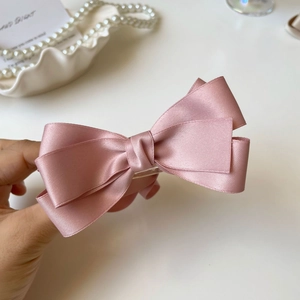 Dettaglio del fermaglio per capelli con fiocco in raso rosa e nastro di seta a strati