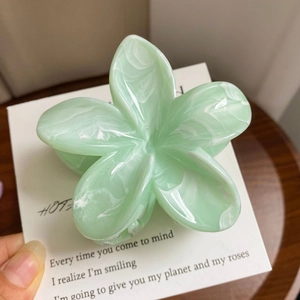 Detail of mint green marble acetate flower hair claw clip on a decorative card
