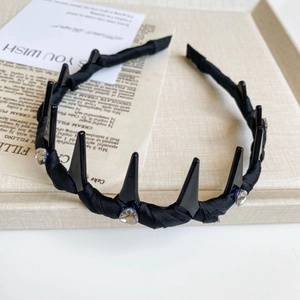 Detailed close-up of a black resin spike headband with sparkling rhinestone accents