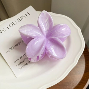 Detail view of a purple marble-patterned frangipani hair claw clip on a white ceramic plate