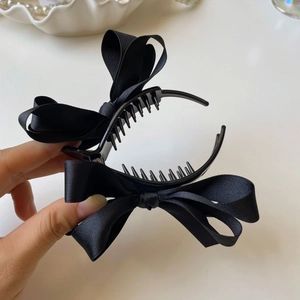 Dettaglio di un grande fermaglio per capelli a fiocco in raso nero opaco con denti e consistenza