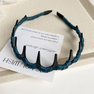 Vue détaillée du serre-tête en tissu vert foncé avec peigne à cheveux noir sur un plateau