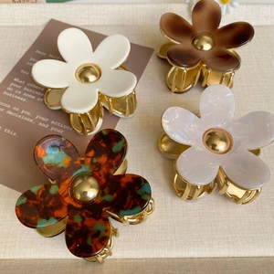 Détail de quatre pinces à cheveux fleur en acétate blanc, marron et motif écaille