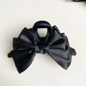 Vista dettagliata di un'elegante pinza per capelli nera con fiocco in raso per acconciature